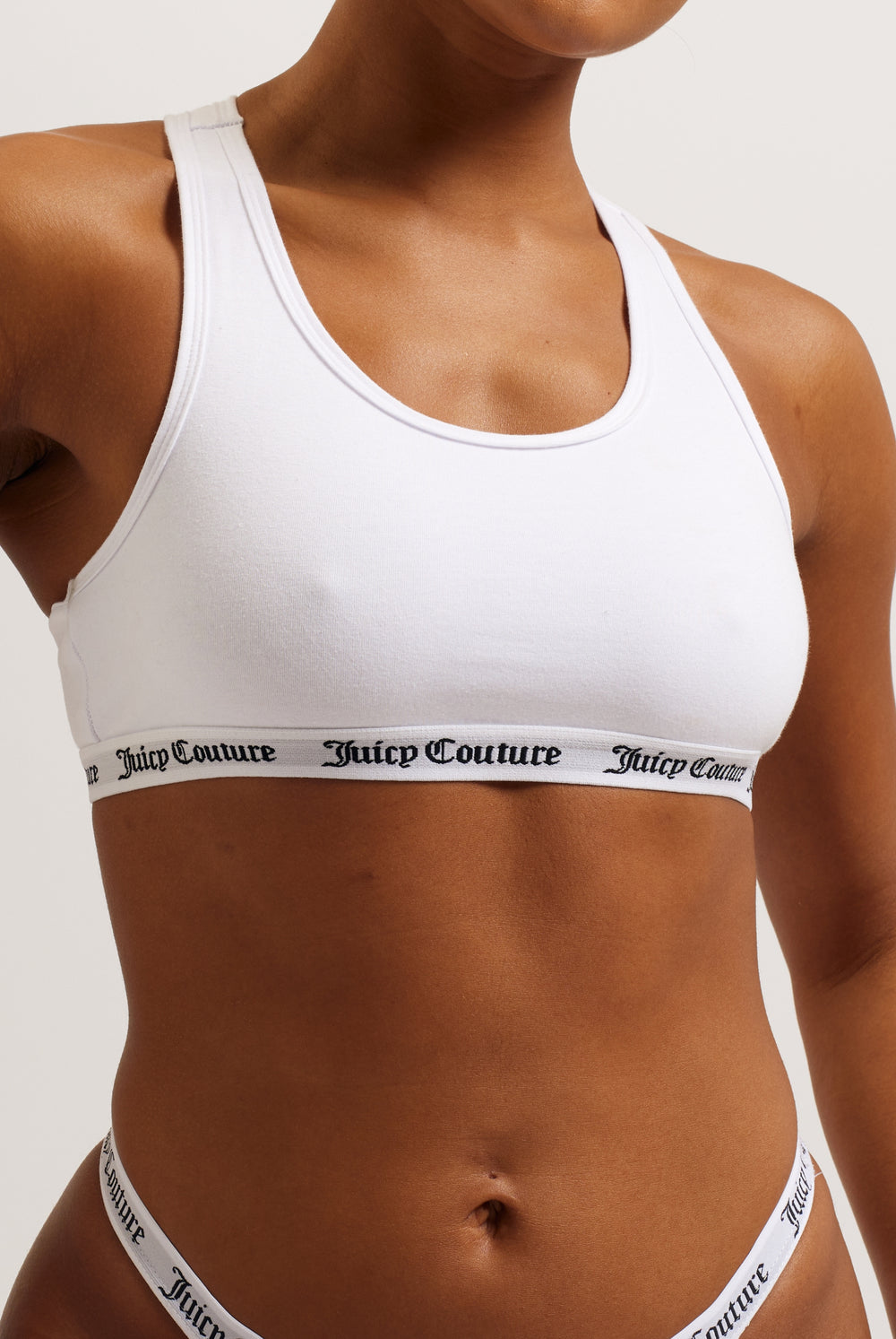 Displays a model wearing the White 'juicy' branded cotton bralette 