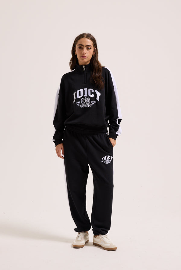 Displays a model wearing the Black 'Juicy' branded college crest track top 