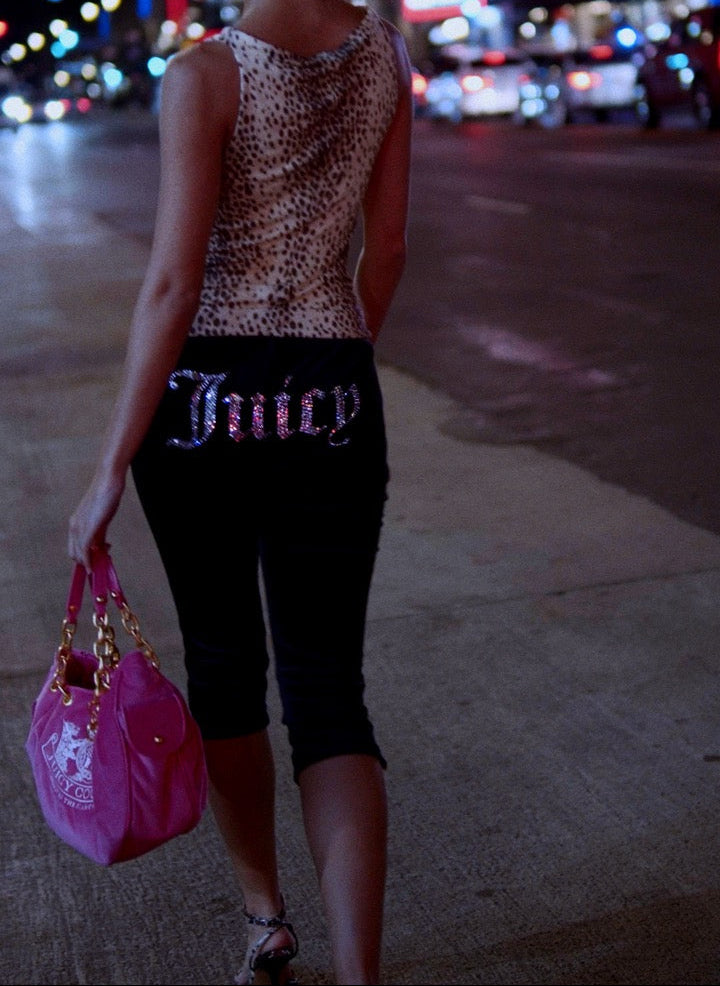 Displays a model wearing the Black Diamanté 'Juicy' branded classic velour capri pants 