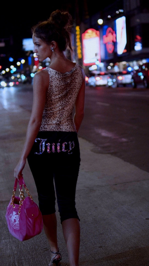 Displays a model wearing the Black Diamanté 'Juicy' branded classic velour capri pants 