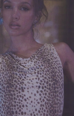 Displays a model wearing the natural cheetah print 'Juicy' off the shoulder top 