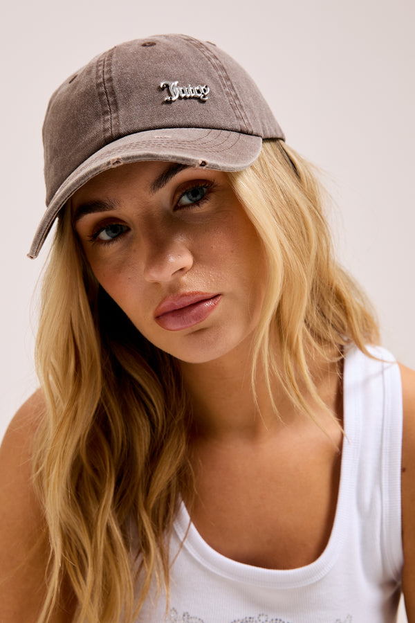 Displays a model wearing the Java 'Juicy' branded distressed cotton denim cap 
