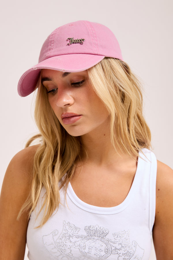 Displays a model wearing the pink 'juicy' branded distressed cotton denim cap 