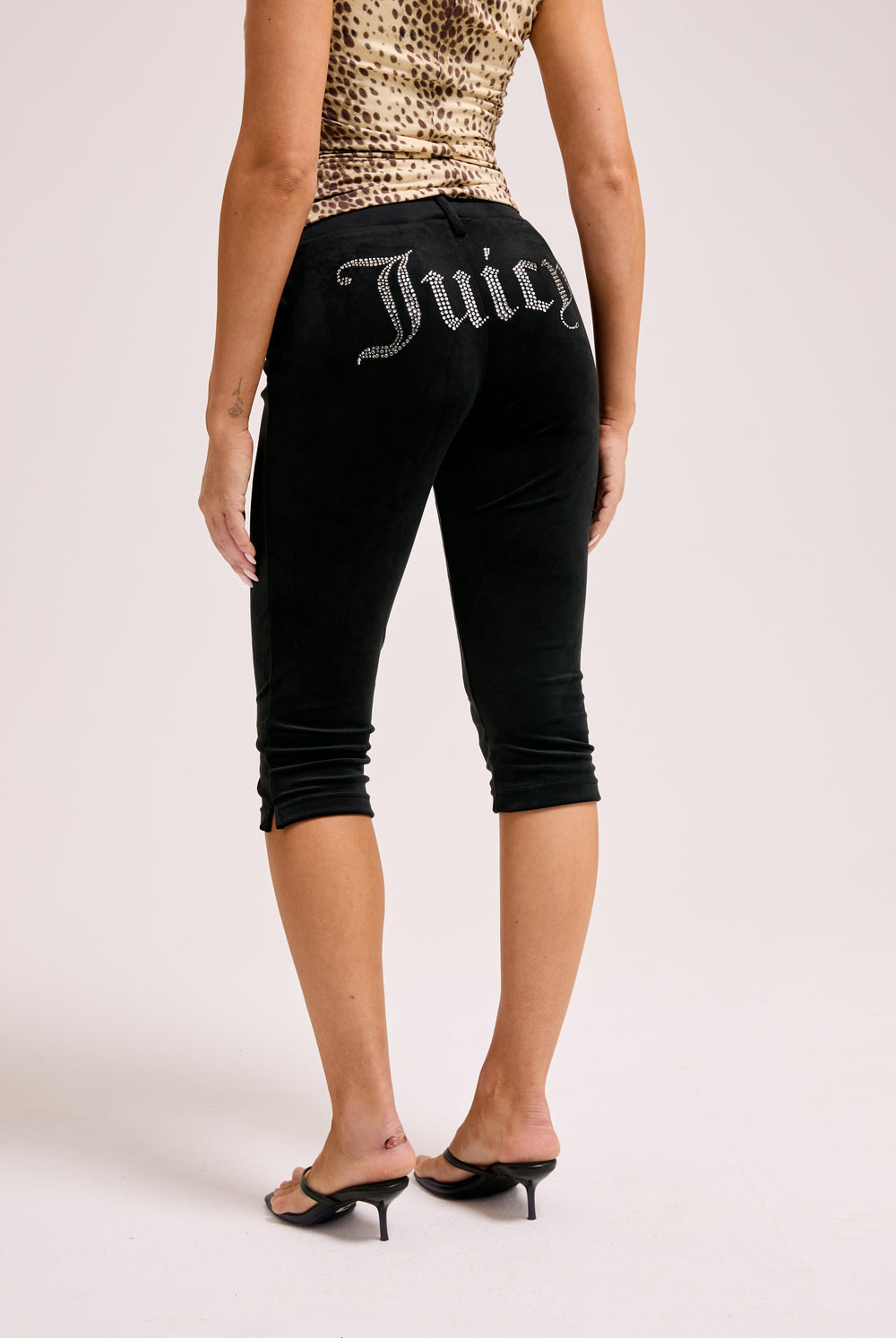 Displays a model wearing the Black Diamanté 'Juicy' branded classic velour capri pants 