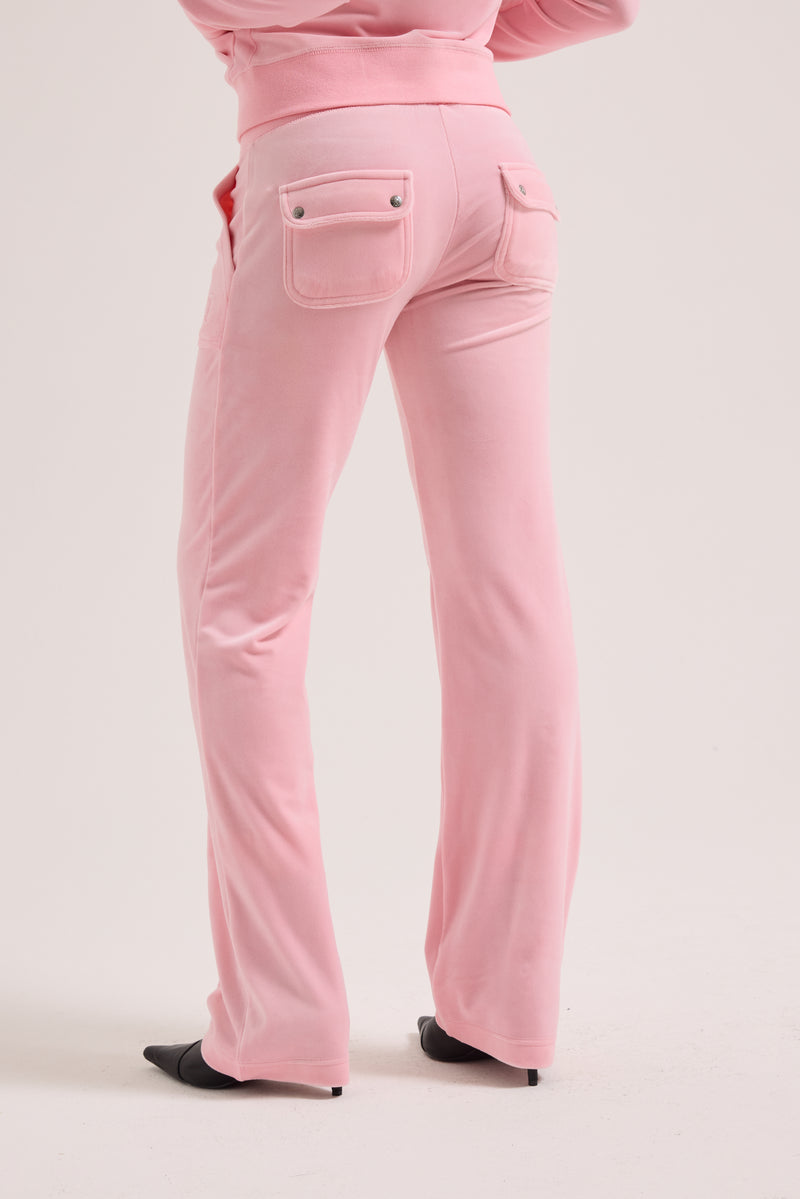 Displays a model wearing the Juicy Pink Classic 'Juicy' branded velour del ray pocketed bottoms