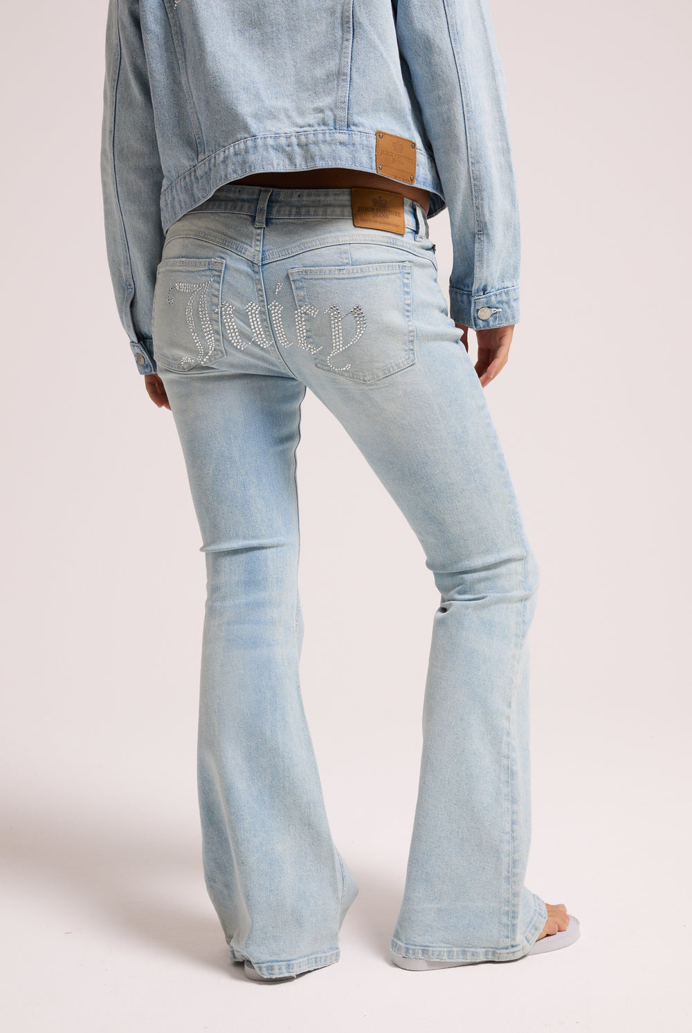 Displays a model wearing the light wash 'Juicy' branded Diamanté low rise flare jeans featuring the juicy branding 