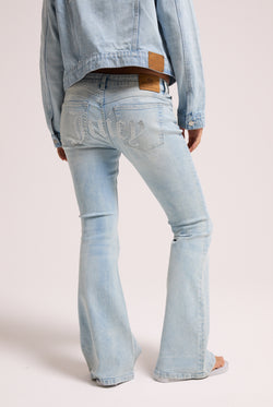 Displays a model wearing the light wash 'Juicy' branded Diamanté low rise flare jeans featuring the juicy branding 