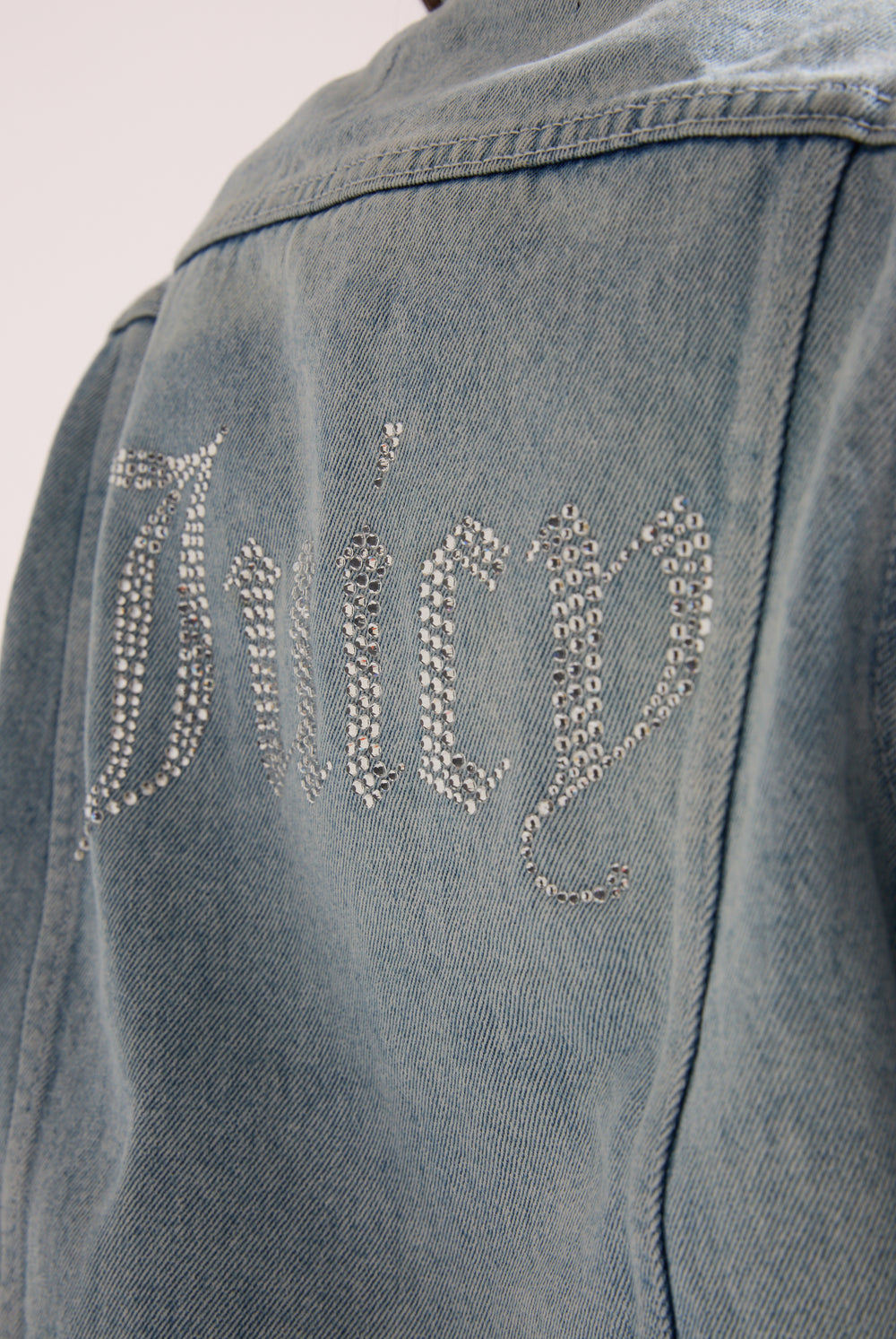 Displays the light wash 'Juicy' branded stretch denim fitted jacket featuring the juicy branding 