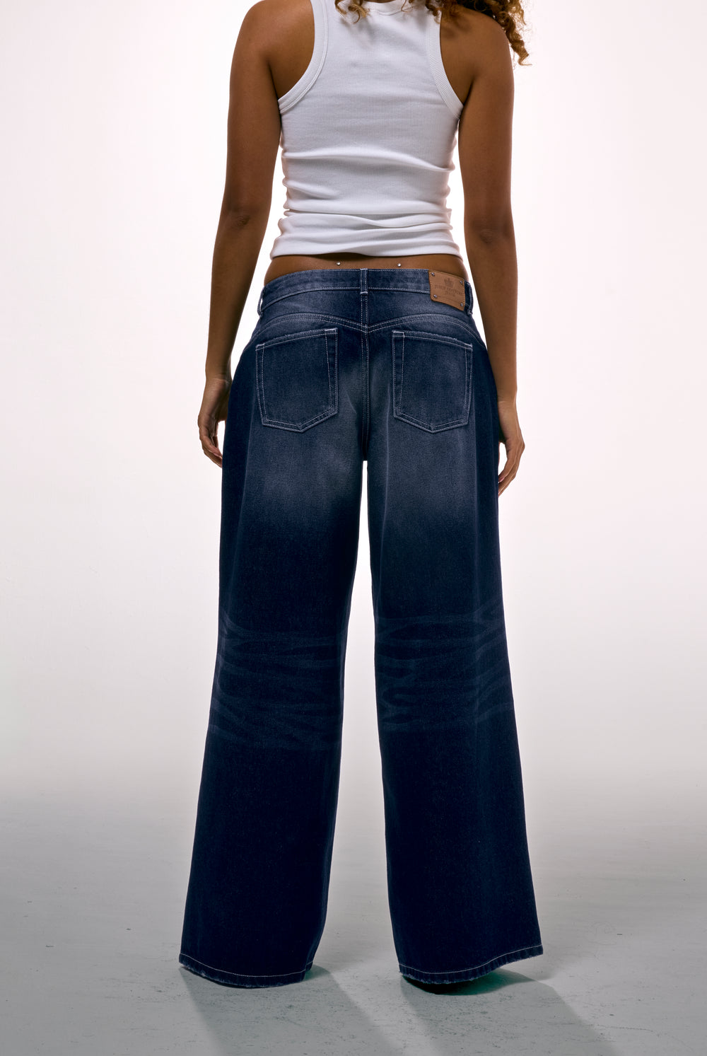 Displays a model wearing the mid Wash 'Juicy' branded wide leg Diamanté jeans 