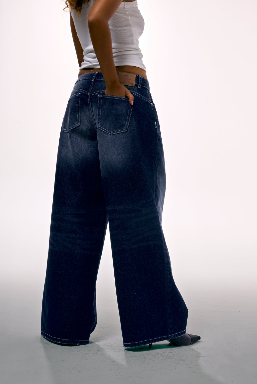 Displays a model wearing the mid Wash 'Juicy' branded wide leg Diamanté jeans 