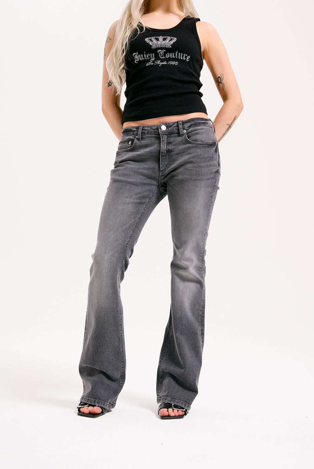 Displays a model wearing the grey wash 'Juicy' branded Digi diamanté mid rise flared jeans 