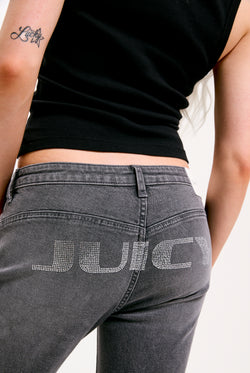 Displays a model wearing the grey wash 'Juicy' branded Digi diamanté mid rise flared jeans featuring the juicy branding 