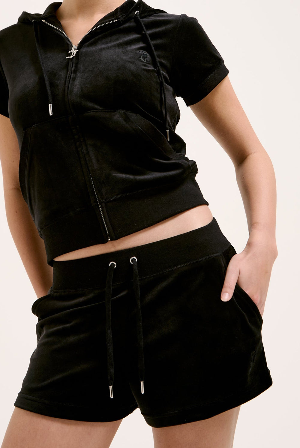 Displays a model wearing the Black 'Juicy' branded classic velour track short with back pocket 