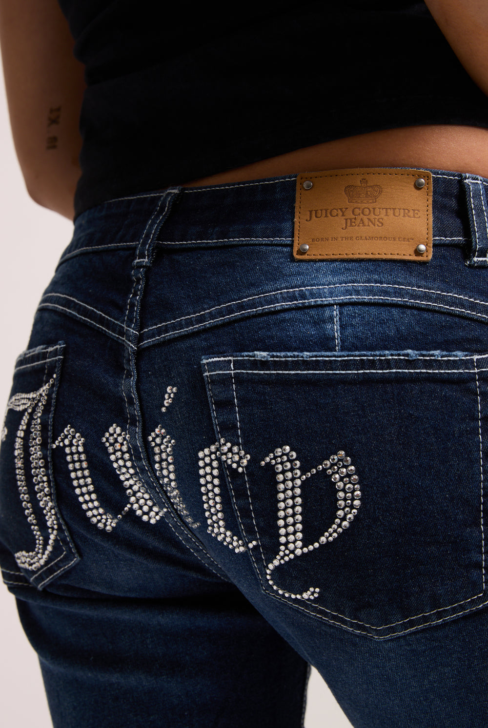 Displays a model wearing the 'Juicy' branded mid wash diamanté low rise flare jeans featuring the juicy branding 