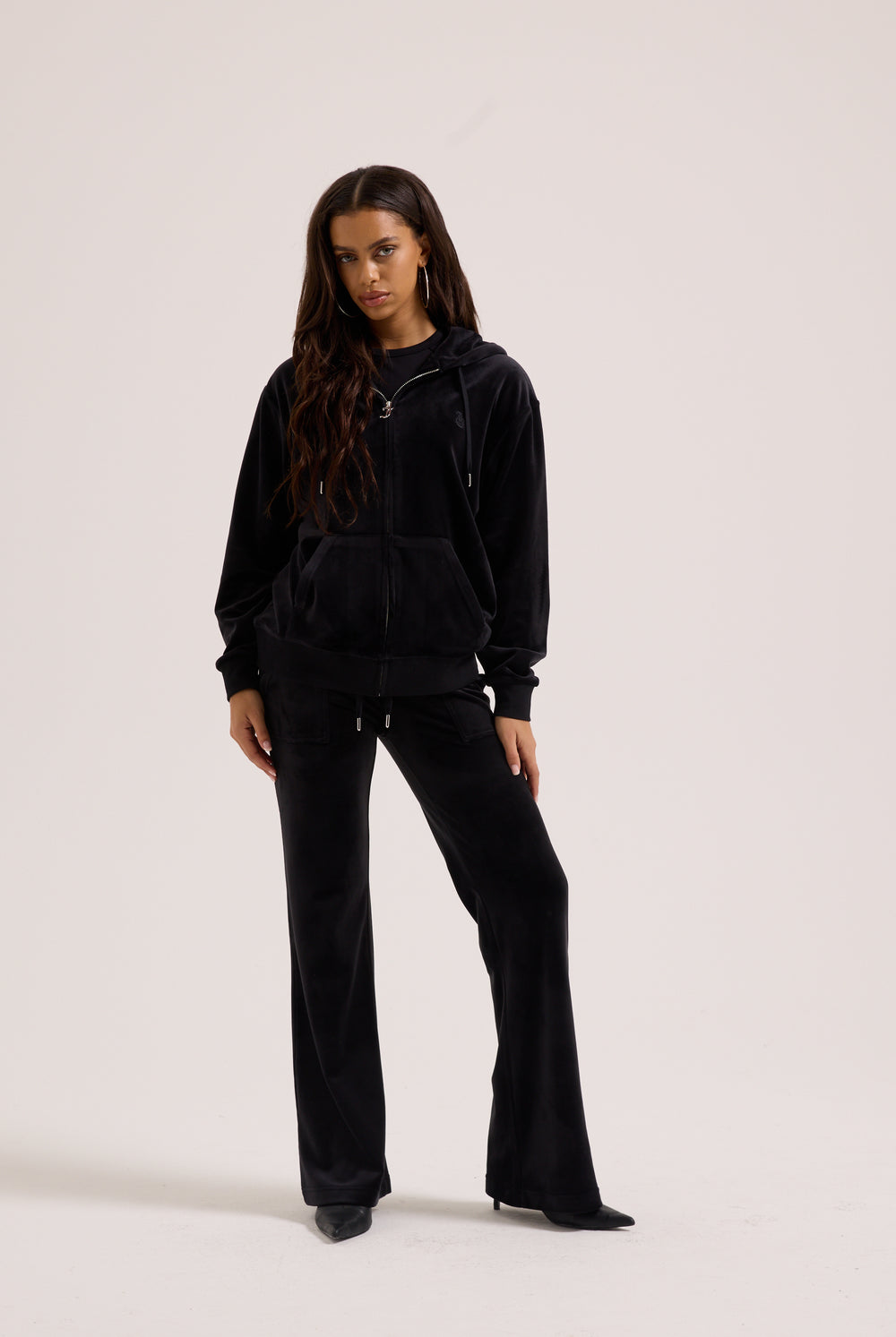 Displays a model wearing the black classic 'Juicy' branded velour oversized hoodie