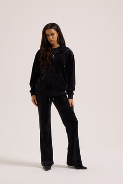 Displays a model wearing the black classic 'Juicy' branded velour oversized hoodie