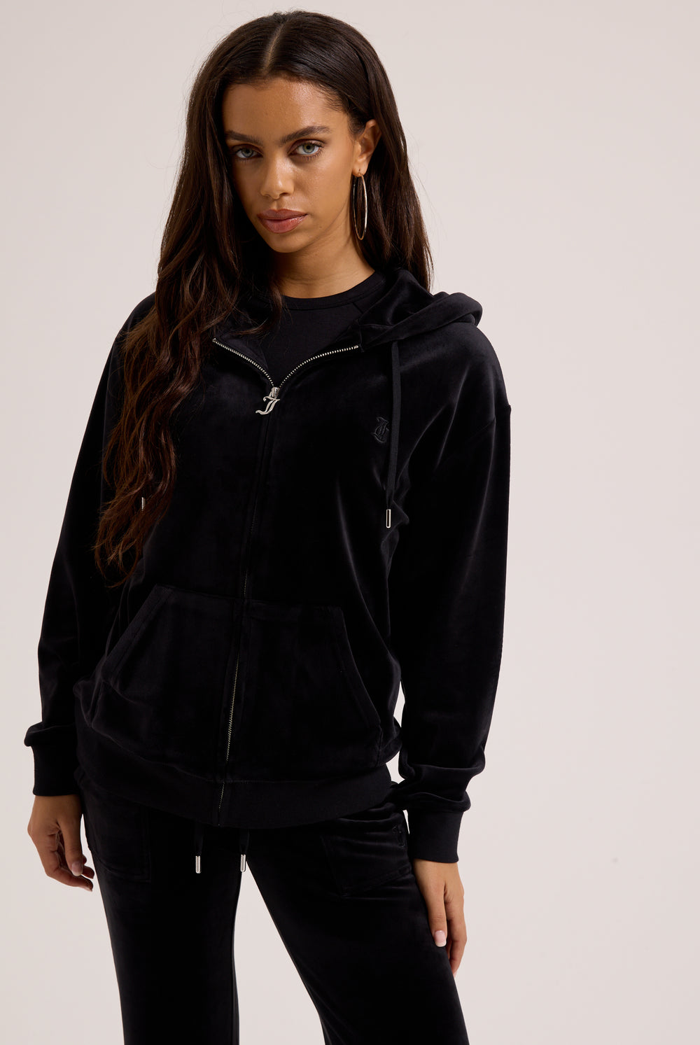 Displays a model wearing the black classic 'Juicy' branded velour oversized hoodie
