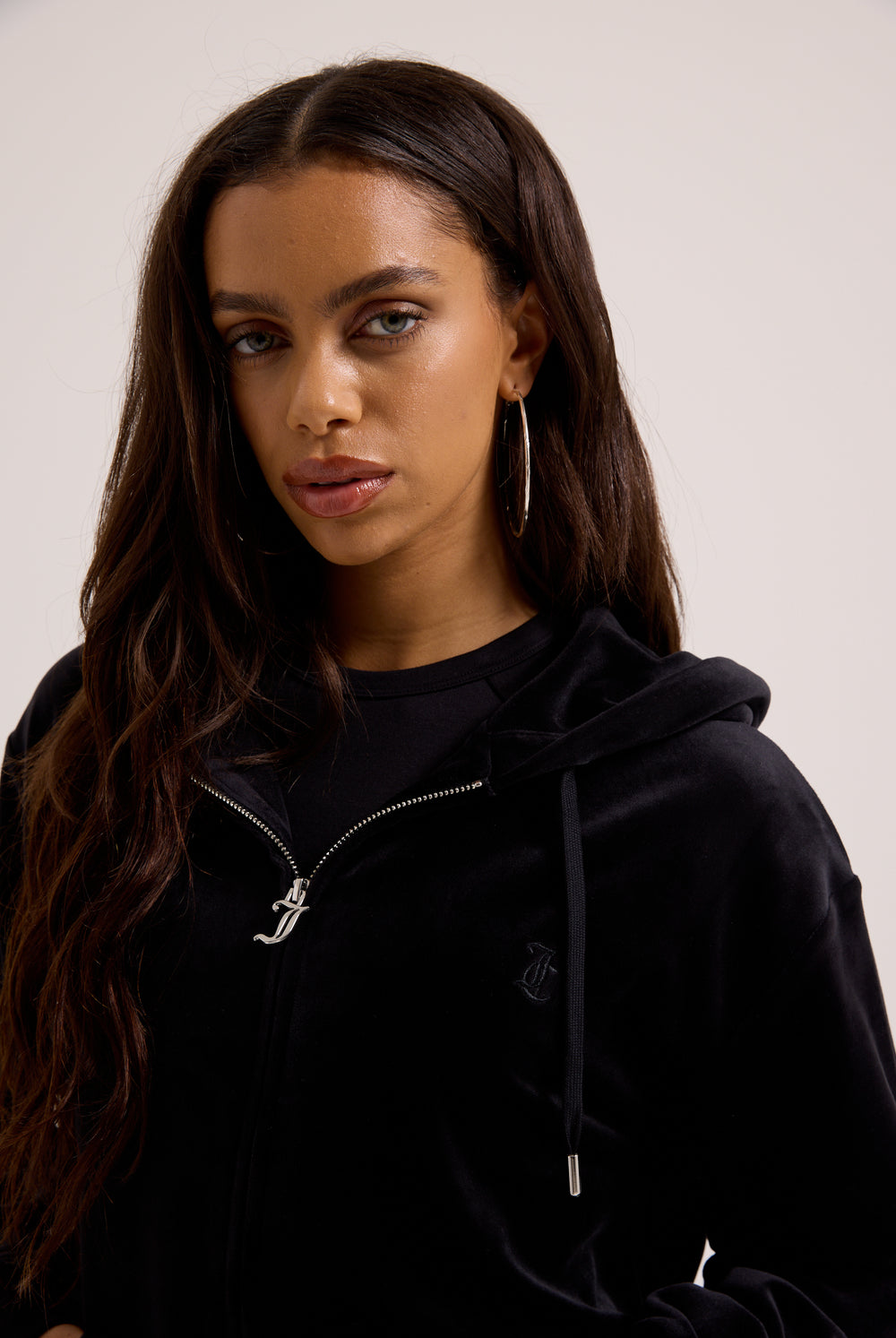 Displays a model wearing the black classic 'Juicy' branded velour oversized hoodie