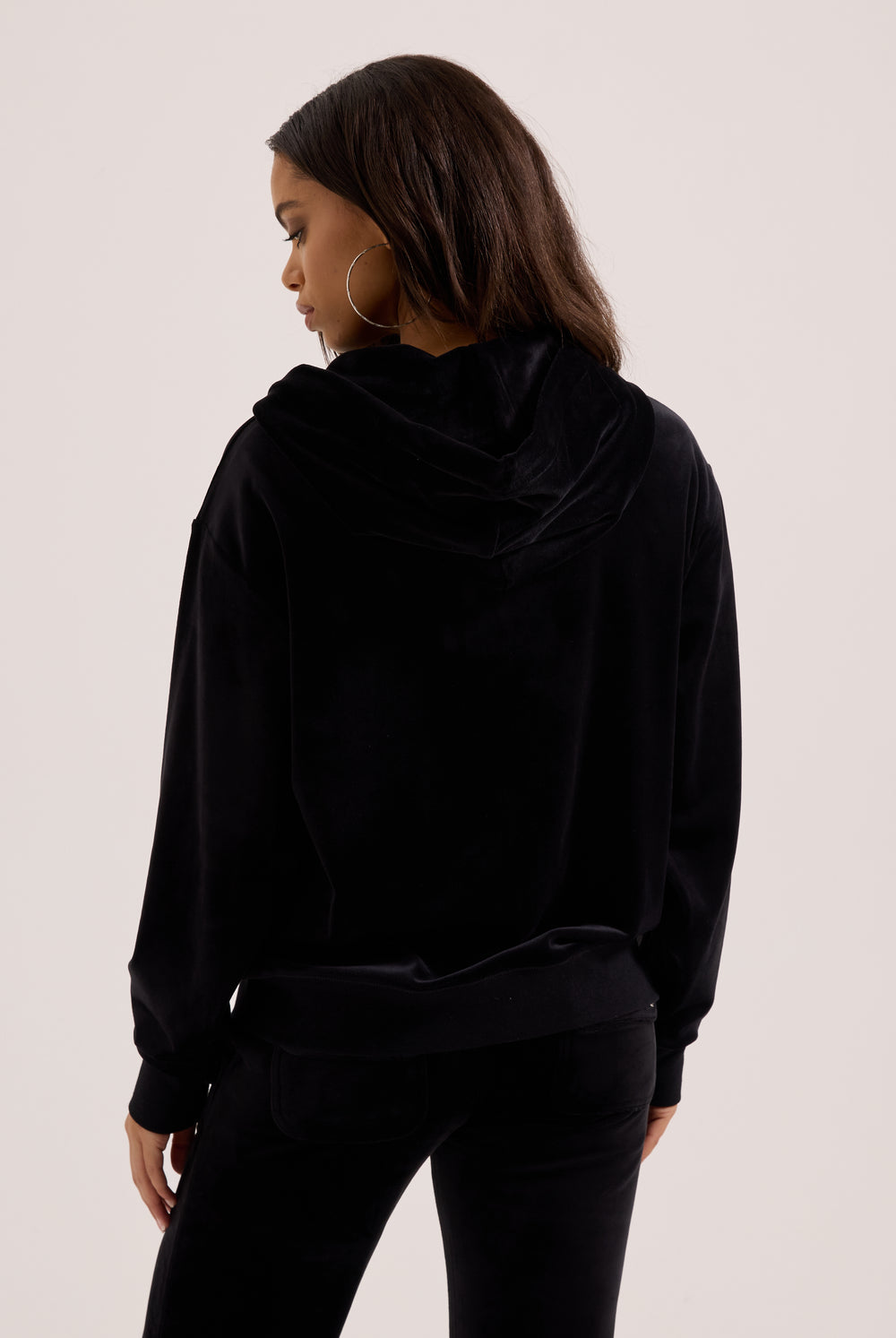Displays a model wearing the black classic 'Juicy' branded velour oversized hoodie