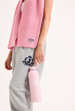 Displays a model holding the Pink 'Juicy' branded heritage crest water bottle 