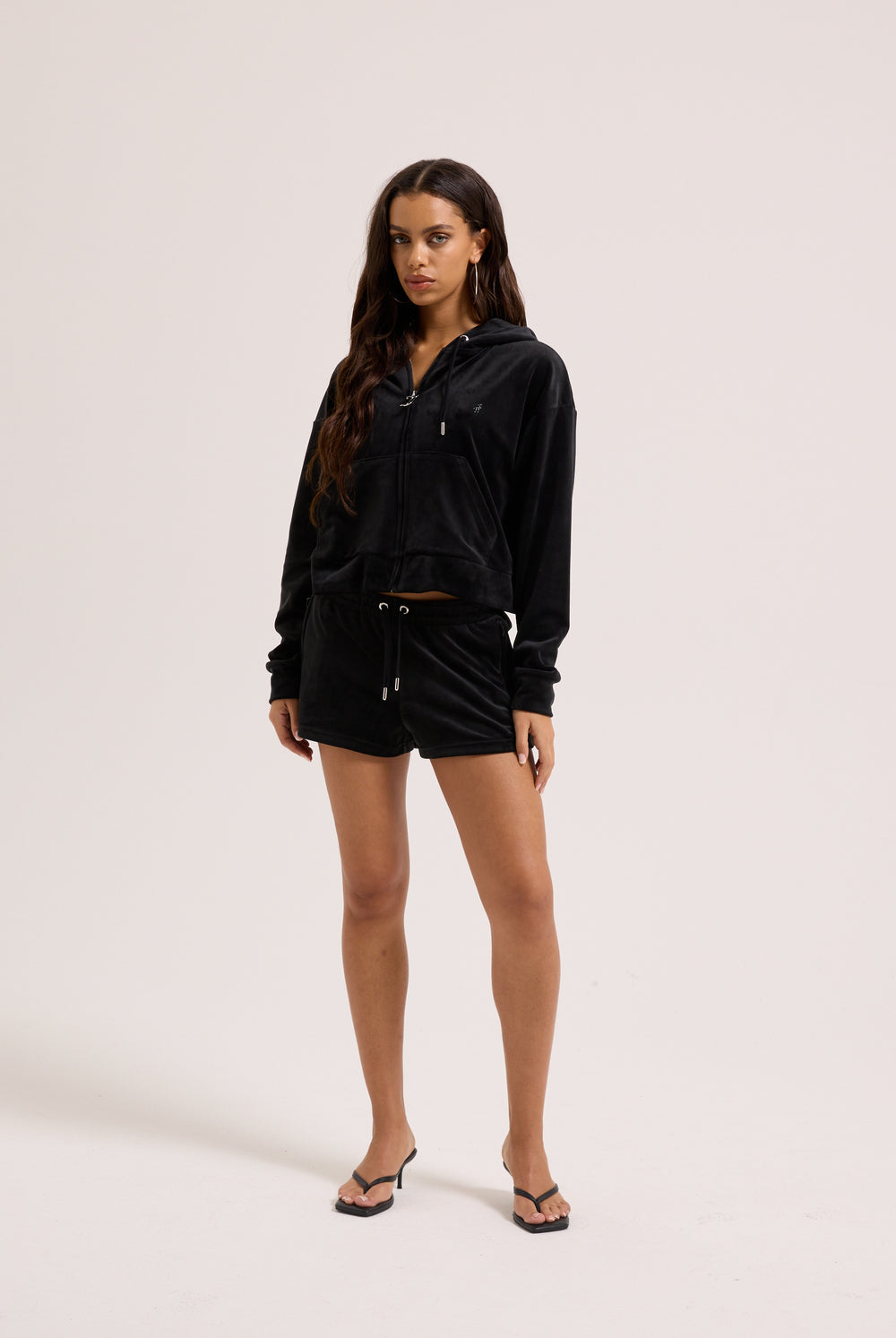 Displays a model wearing the Black 'Juicy' branded velour outline diamanté track shorts 