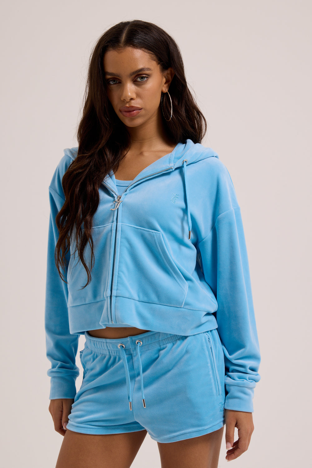 Displays a model wearing the Sky Blue 'juicy' branded Velour outline diamanté track shorts 
