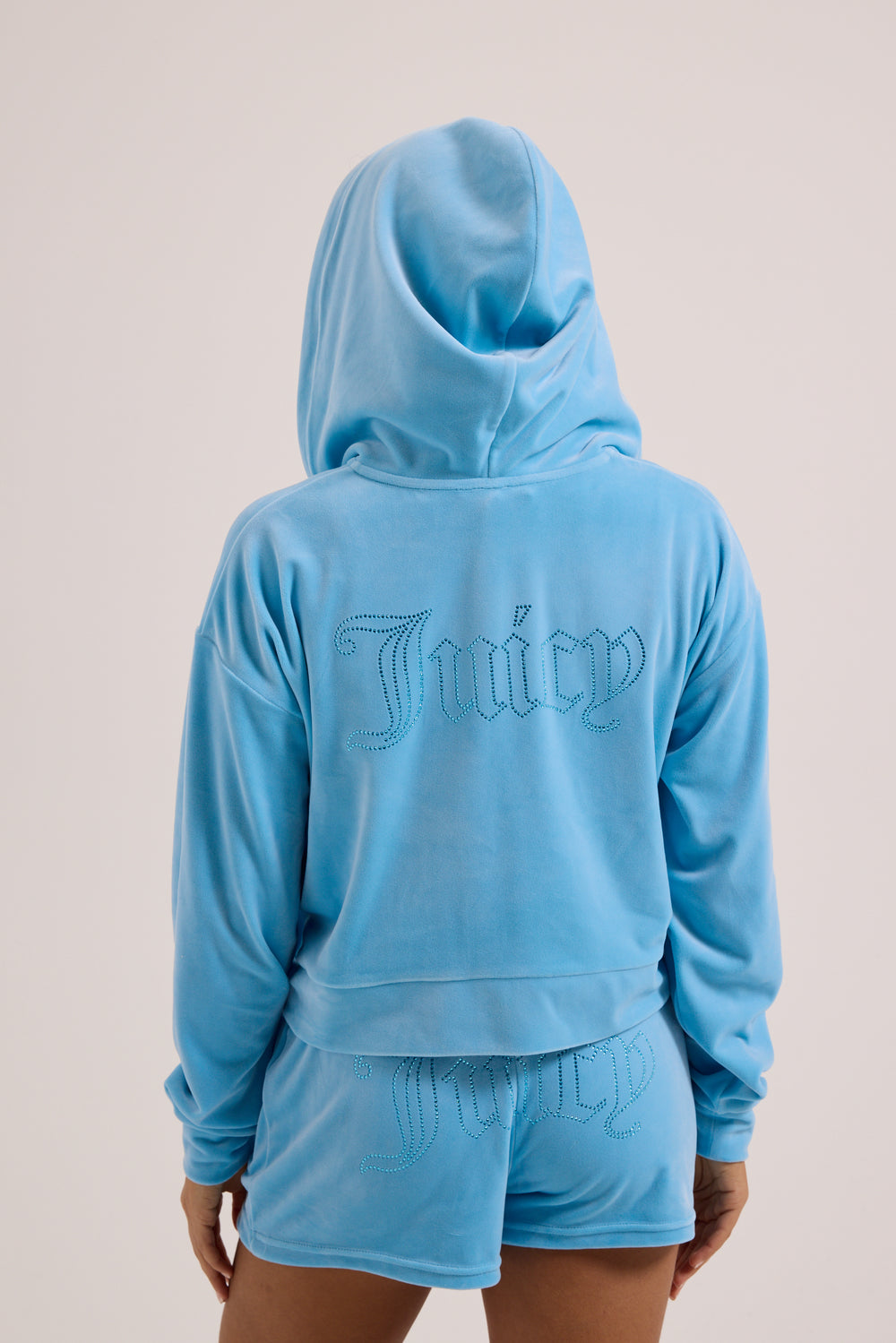 Displays a model wearing the Sky Blue 'juicy' branded Velour outline diamanté track shorts 