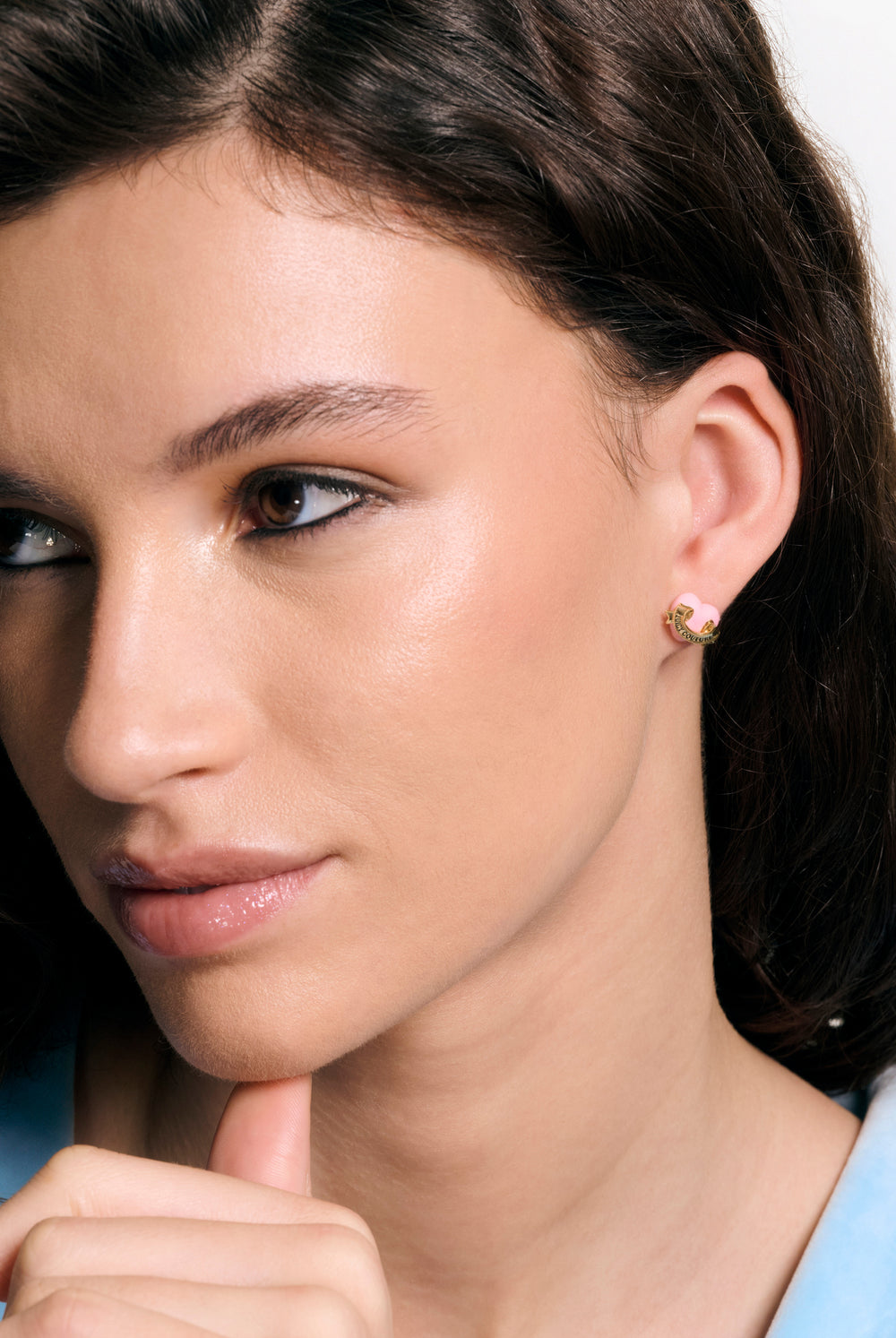 Displays a model wearing the Gold tone 'Juicy' branded enamel icon heart stud earrings 