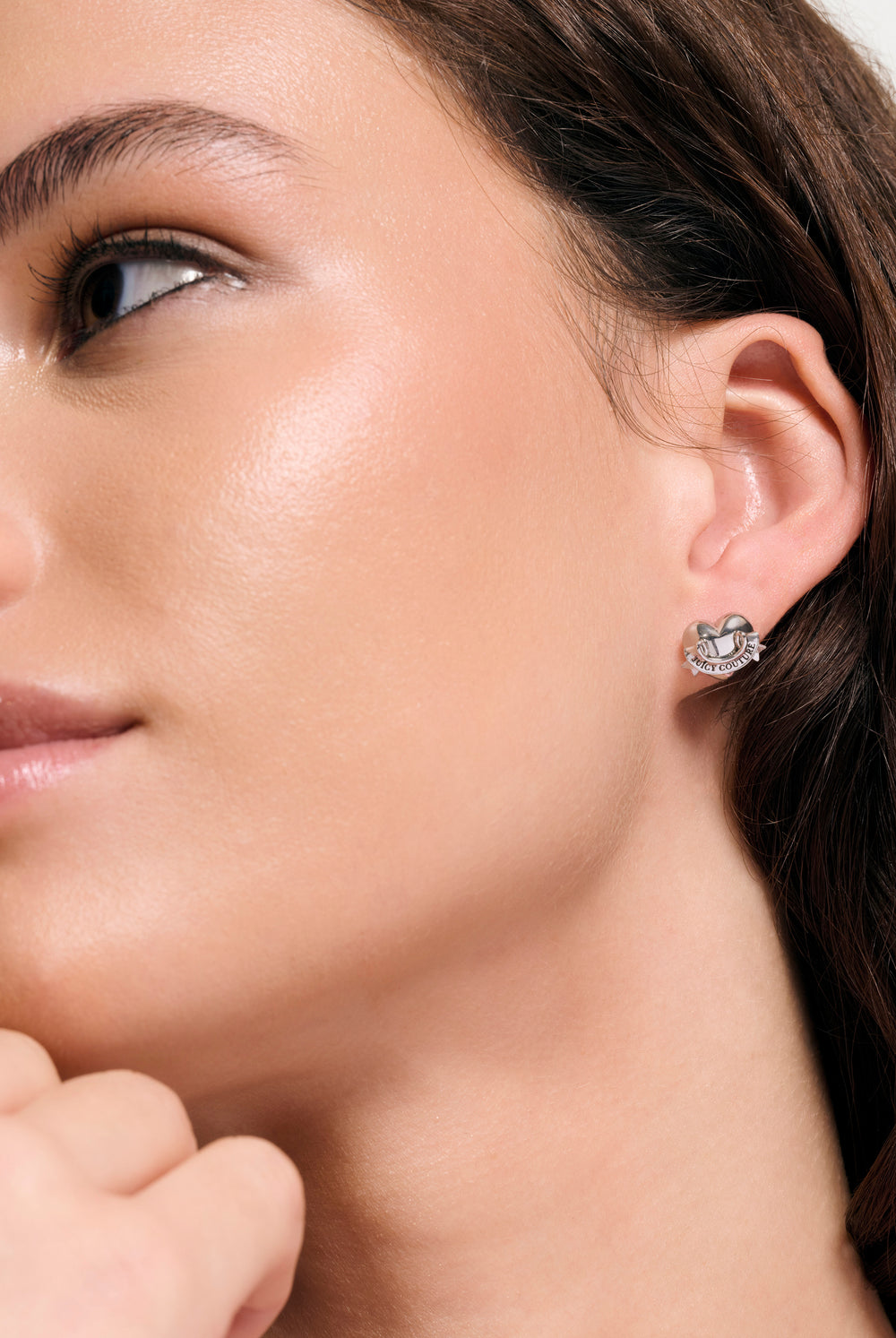 Displays a model wearing the Silver Tone 'Juicy' icon heart stud earrings 