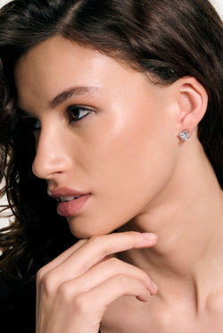 Displays a model wearing the Silver Tone 'Juicy' branded solitaire crystal heart stud earrings