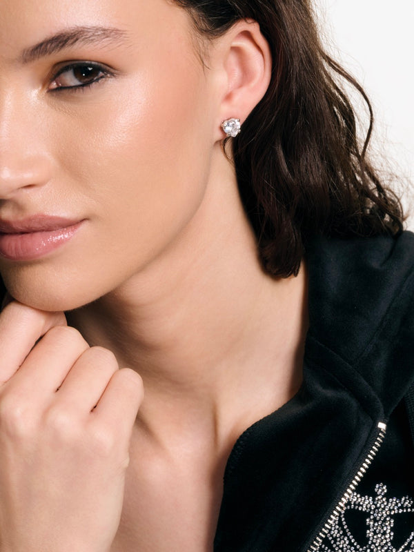 Displays a model wearing the 'Juicy' Silver Tone Solitaire Crystal Heart Stud Earring