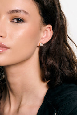 Displays a model wearing the Gold Tone 'Juicy' branded solitaire crystal heart stud earrings