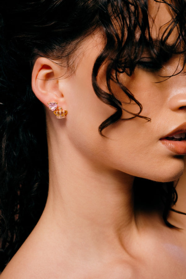 Displays a model wearing the 'Juicy' Gold Tone Solitaire Crystal Heart Stud Earrings