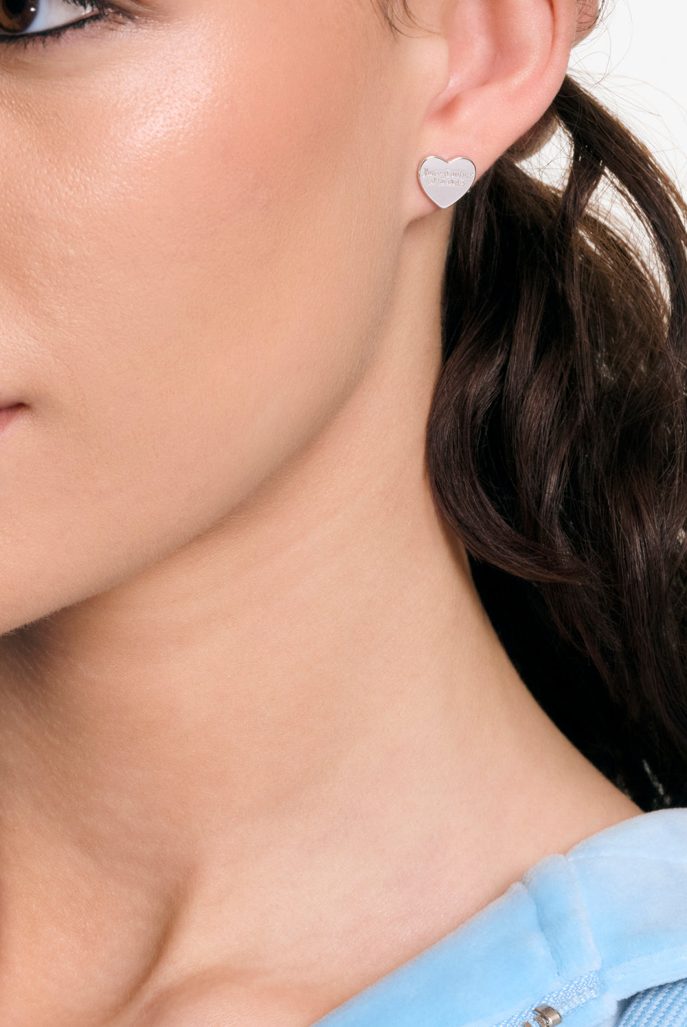 Displays a model wearing the Silver Tone 'Juicy' branded heart stud earrings 