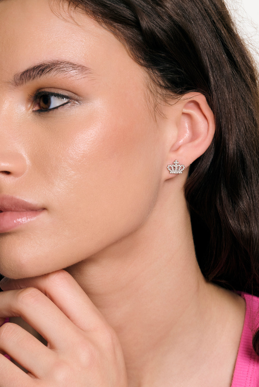 Displays a model wearing the silver tone 'juicy' branded crystal motif crown stud earrings 