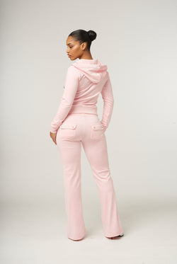 Displays a model wearing the almond blossom 'Juicy' branded low rise flare classic velour track pant 
