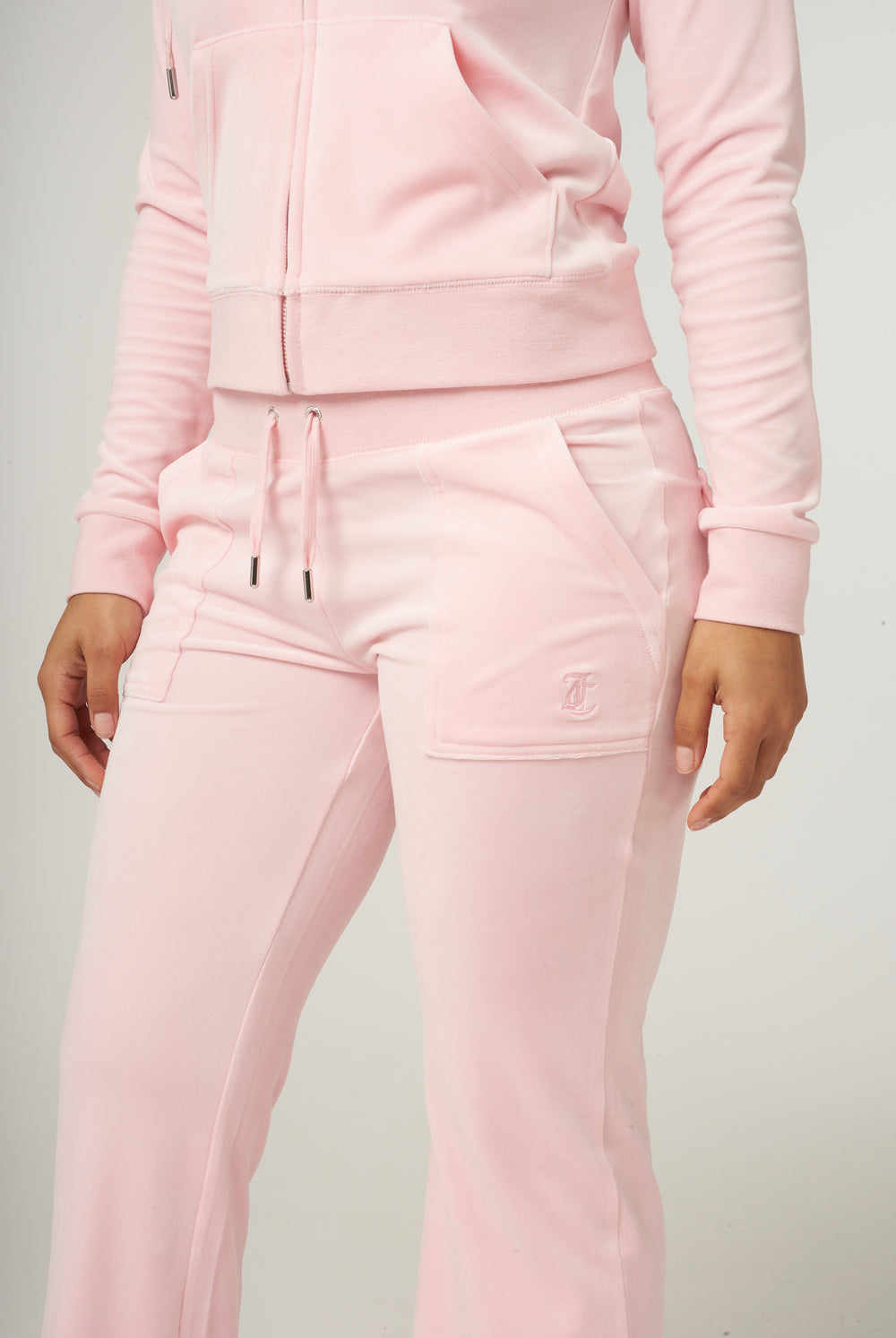 Displays a model wearing the almond blossom 'Juicy' branded low rise flare classic velour track pant 