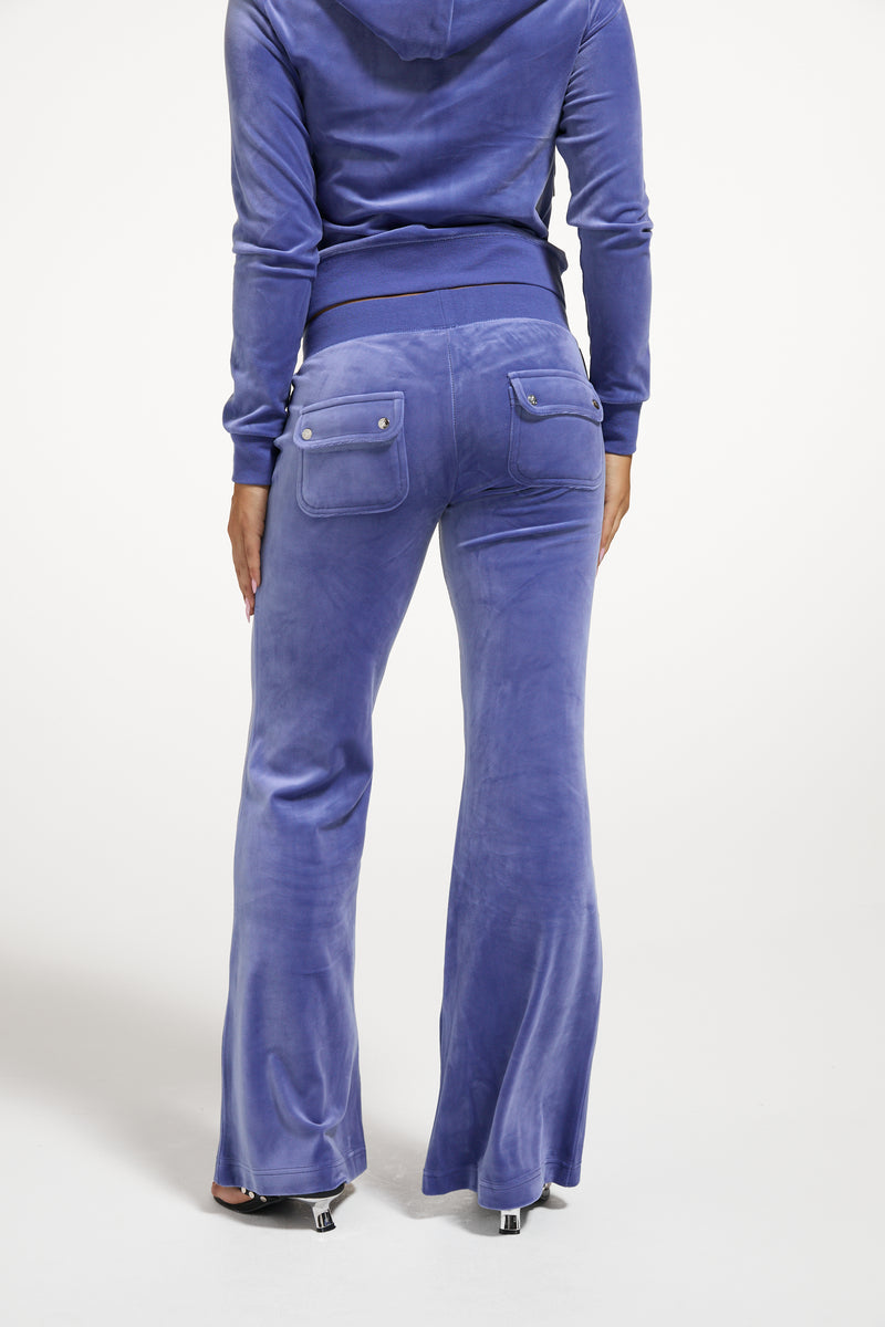 Displays a model wearing the Grey&blue 'Juicy' branded Low Rise Flare Classic Velour Track Pant