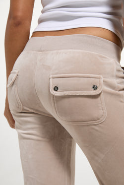 Displays a model wearing the String 'Juicy' branded low rise flare pocket classic velour track pant 