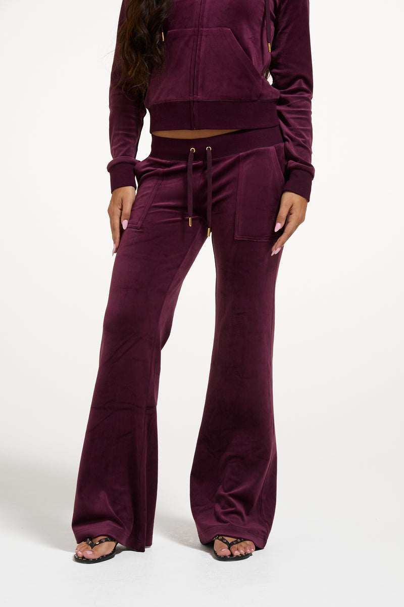 Displays a model wearing the Winetasting & Gold 'Juicy' branded Low Rise Flare Classic Velour Track Pant