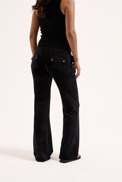 Displays a model wearing the Black Low rise flare pocket 'Juicy' branded classic velour track pant