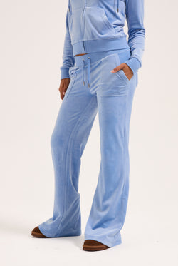 Displays a model wearing the Della Robia 'Juicy' branded low rise flare classic velour track pant 