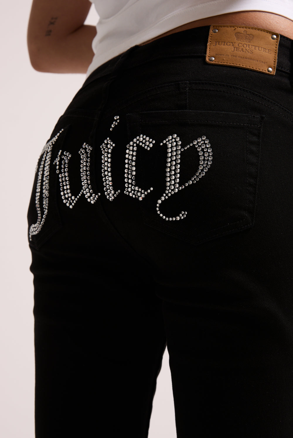 Displays a model wearing the Black stretch 'Juicy' branded twill low rise flare jeans featuring the juicy branding 