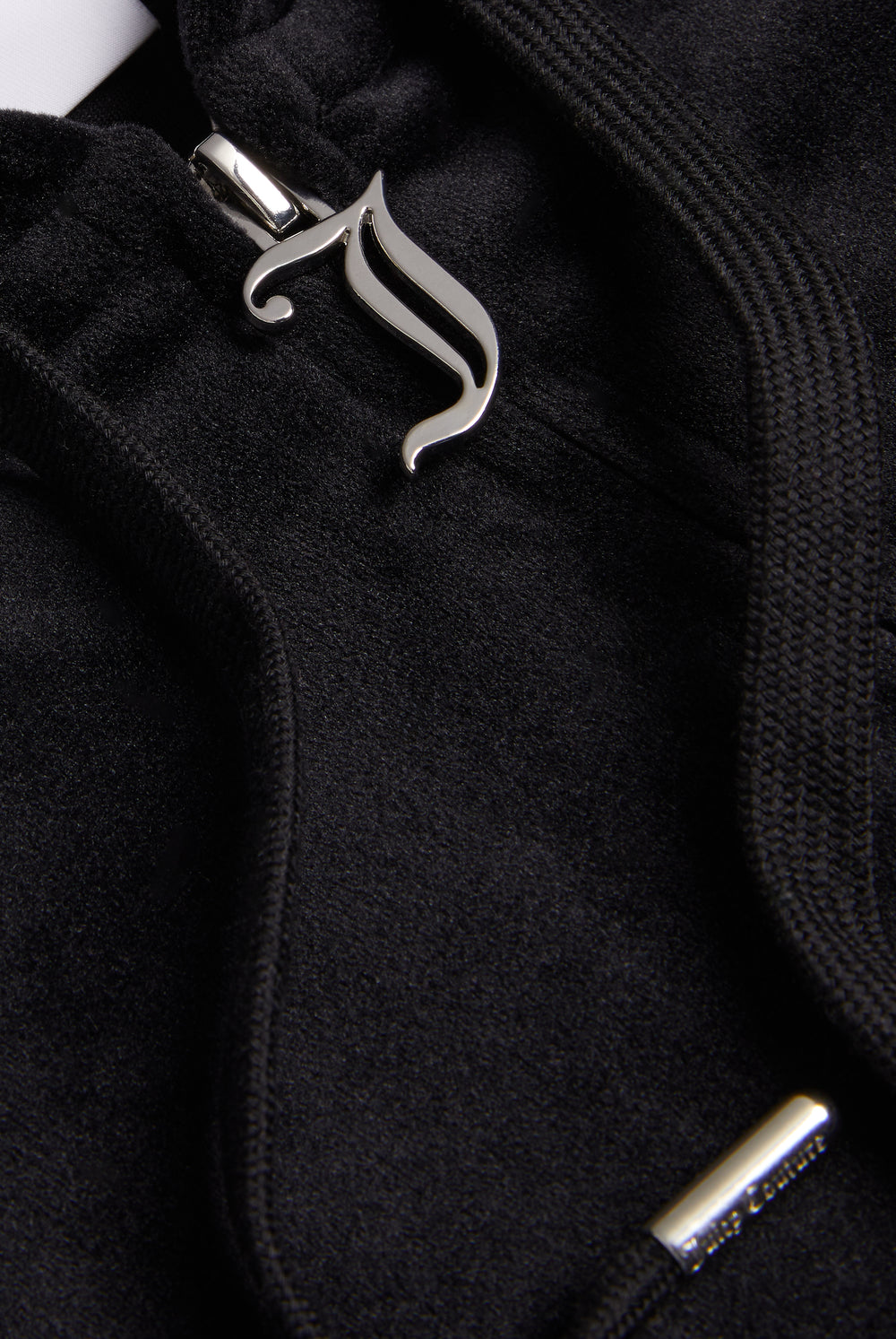 Close-up of the silver Juicy Couture zip detailing on a black velour hoodie