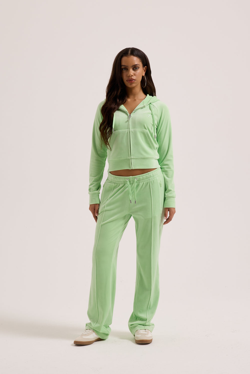 Displays a model wearing the pistachio green outline 'Juicy' branded velour diamanté tracksuit bottom 