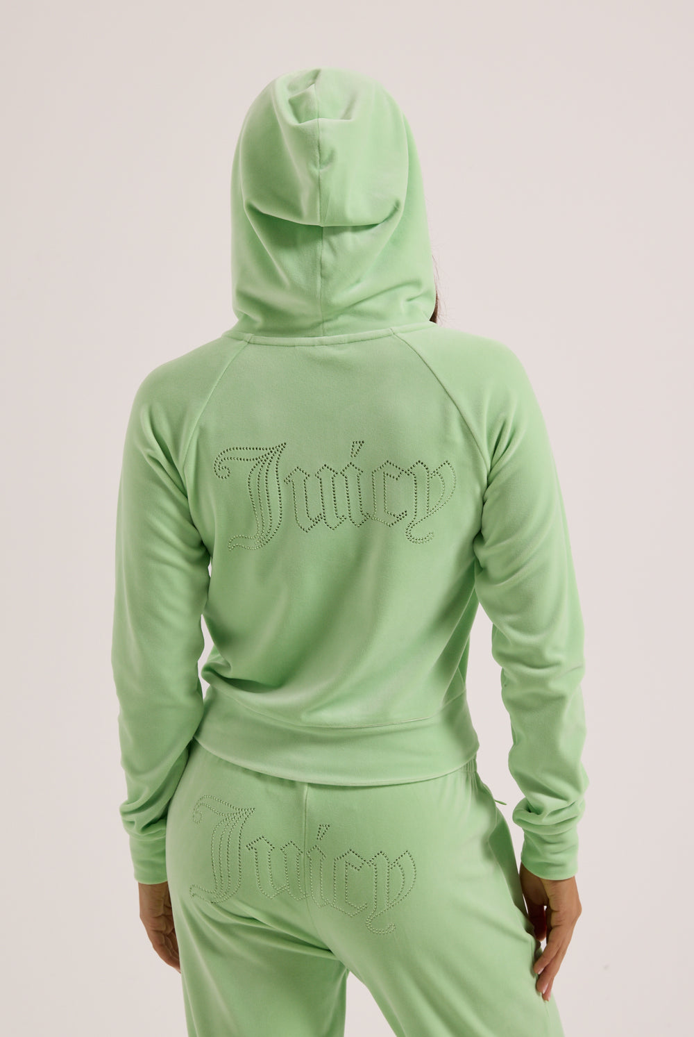 Displays a model wearing the Pistachio Green outline 'Juicy' branded diamanté velour zip-through hoodie 