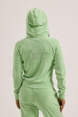 Displays a model wearing the Pistachio Green outline 'Juicy' branded diamanté velour zip-through hoodie 