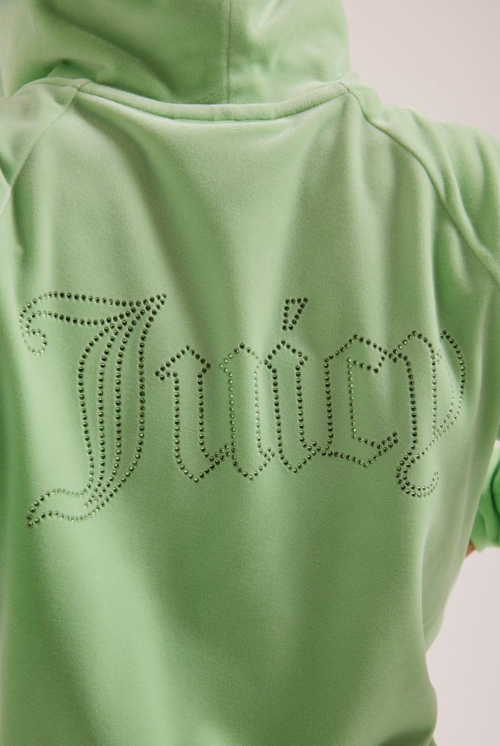 Displays a model wearing the Pistachio Green outline 'Juicy' branded diamanté velour zip-through hoodie featuring the juicy branding 