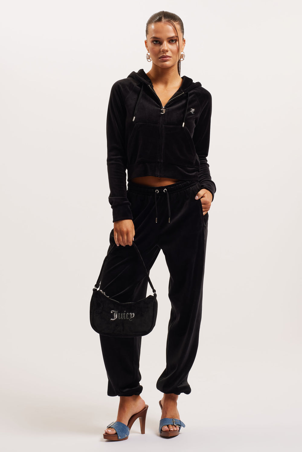 Woman wearing a black tracksuit with a handbag on a white background