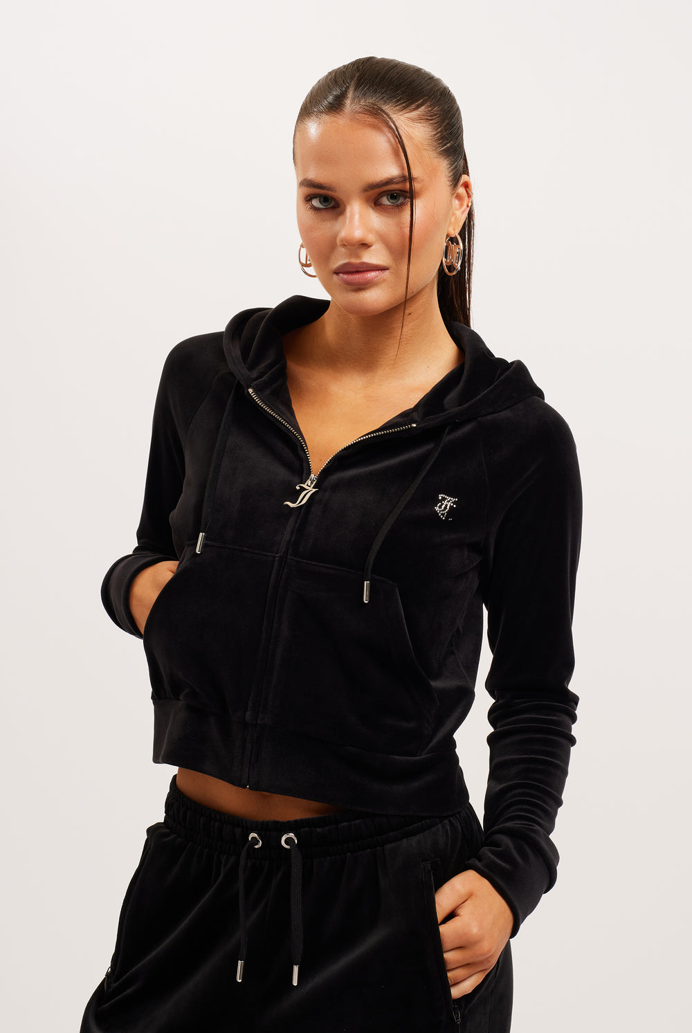 Woman wearing a black tracksuit with a Juicy Couture logo on a white background